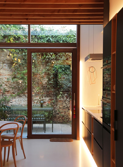 Zwarte nieuwe keuken met ontbijttafel en grote schuifdeur naar terras in rijwoning centrum Gent